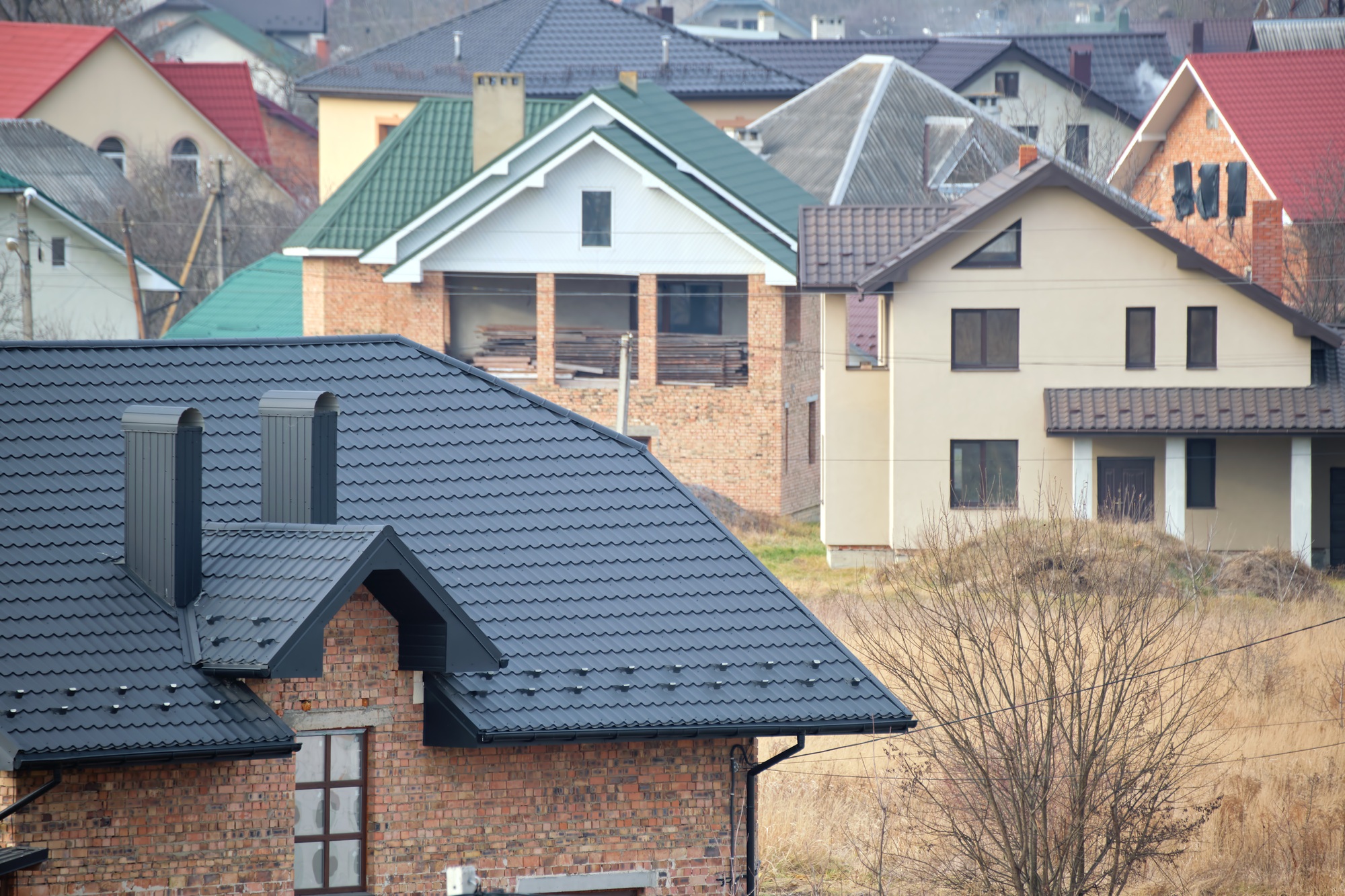 Chimney on house roof top covered with metallic shingles under construction
