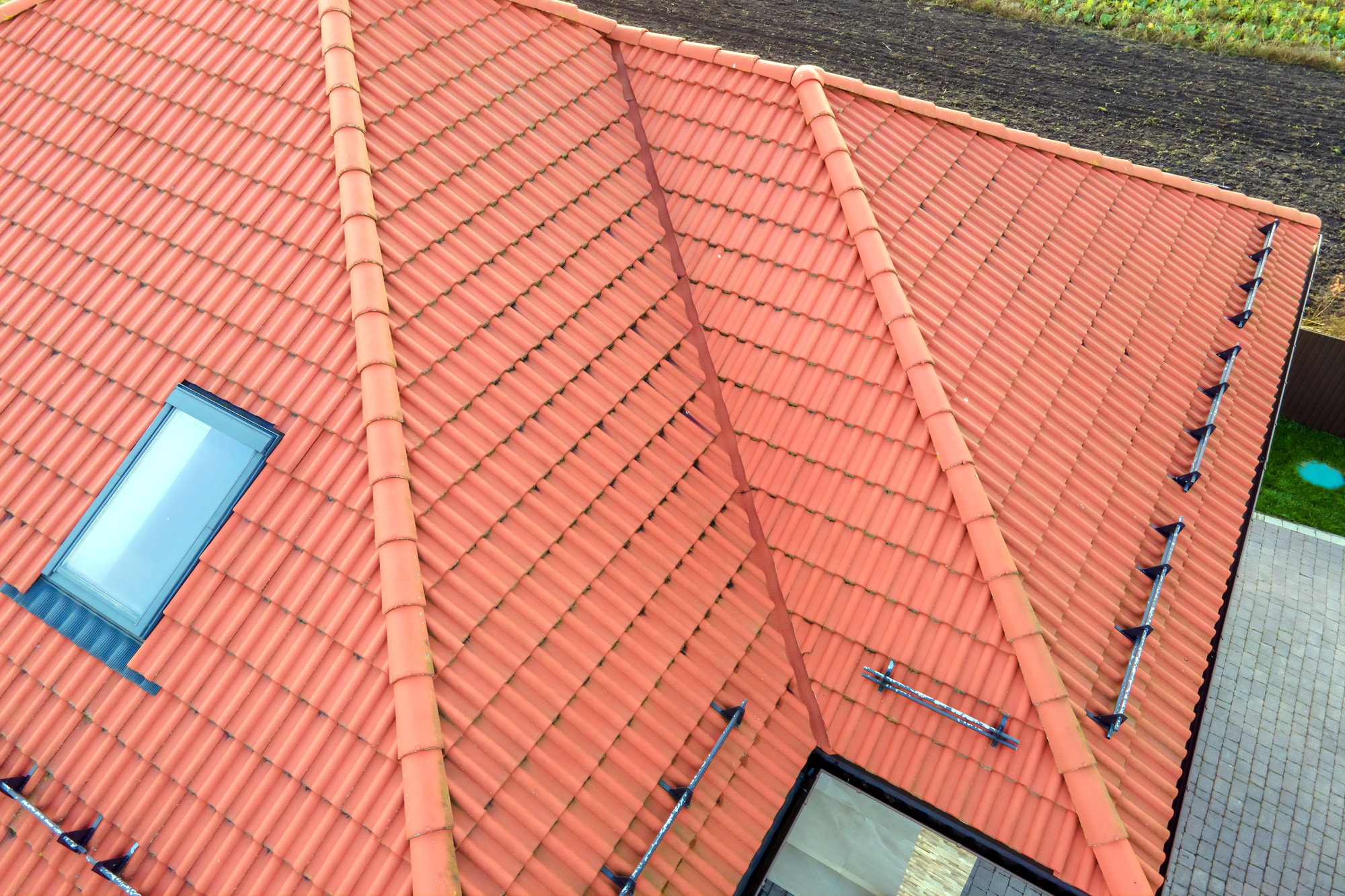 Closeup of house brick roof with yellow shingles cover and attic glass windows